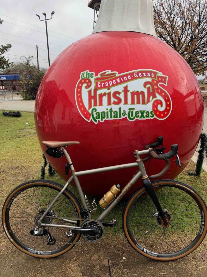 foto bikerumor del giorno in cui una bicicletta si appoggia a un gigantesco ornamento natalizio rosso